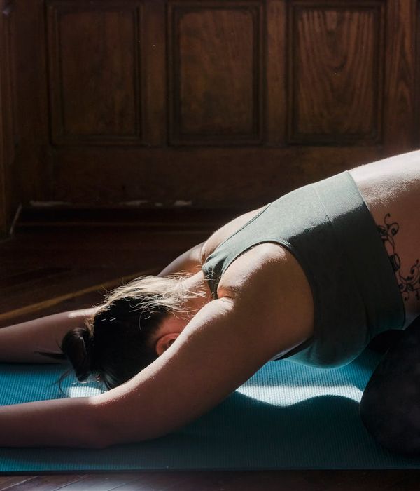 Person stretching peacefully on a yoga mat with soft morning light.